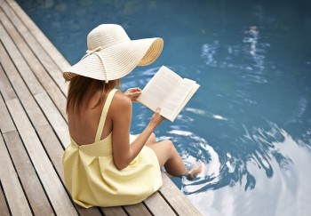 young woman relaxing at the pool with a book