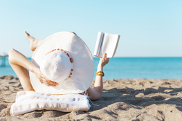 Woman with hat reading on beach