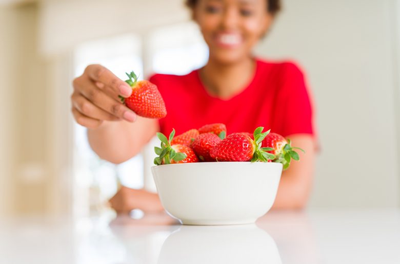woman eating strawberry following a sugar free diet