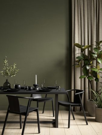 a dark green wall and black tables and chair