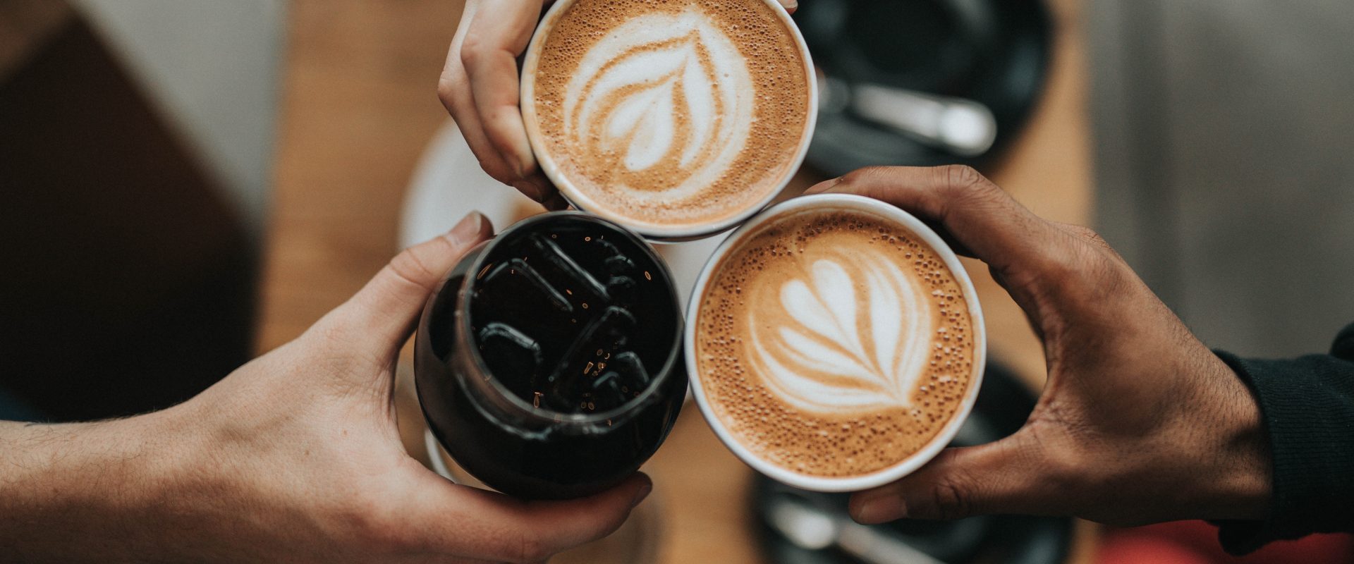 three people holding their cups of coffee together