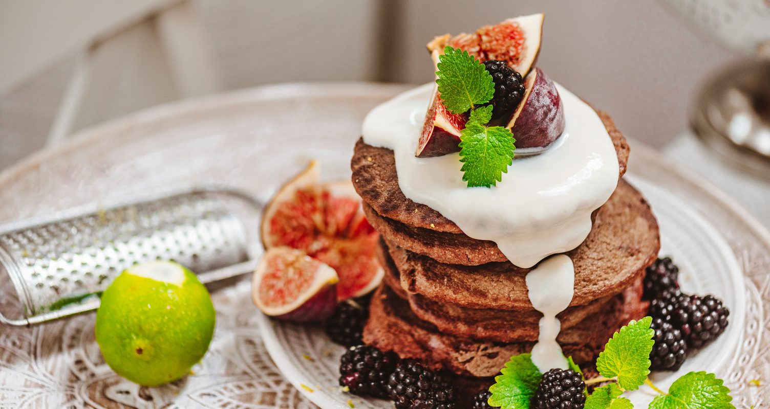 a vegan pancake stack with fruit decorated around it