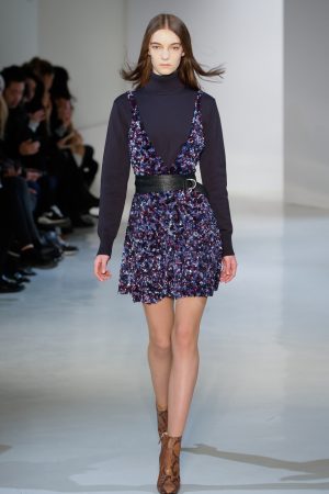 a model walking the runway in a summer dress and turtle neck