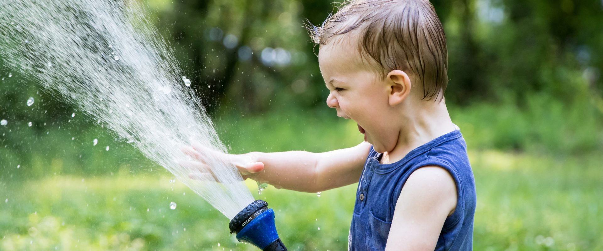 a kid playing with a hosepipe