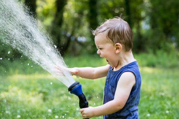 a kid playing with a hosepipe