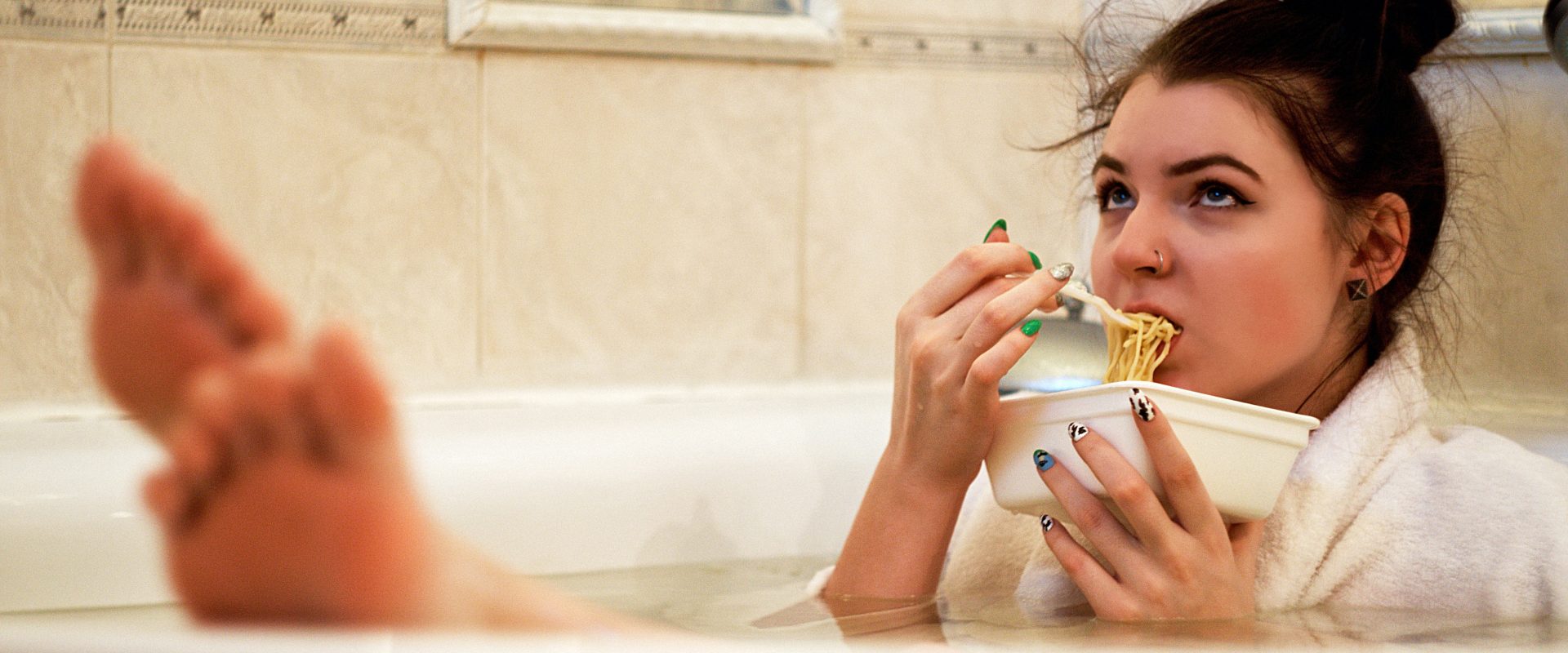 a woman in a bath eating pasta