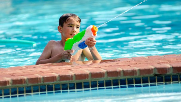 a boy in a pool with a water gun