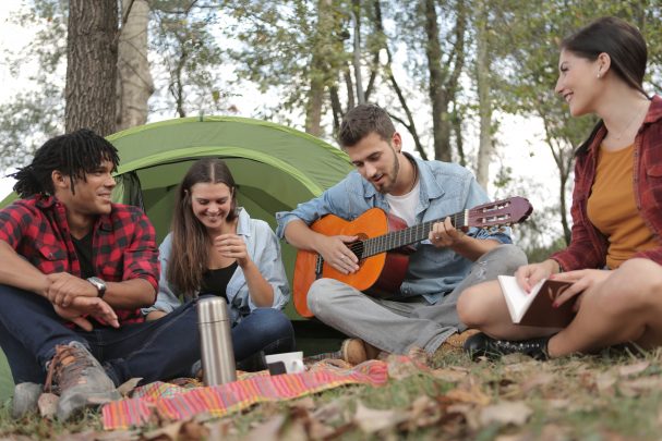 a group of friends at a picnic with a guitar