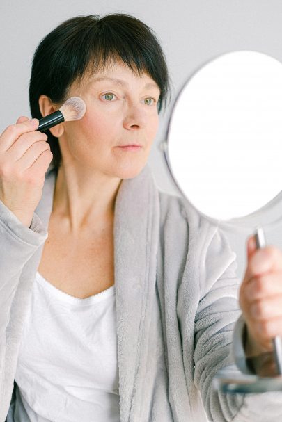 Older woman putting on makeup